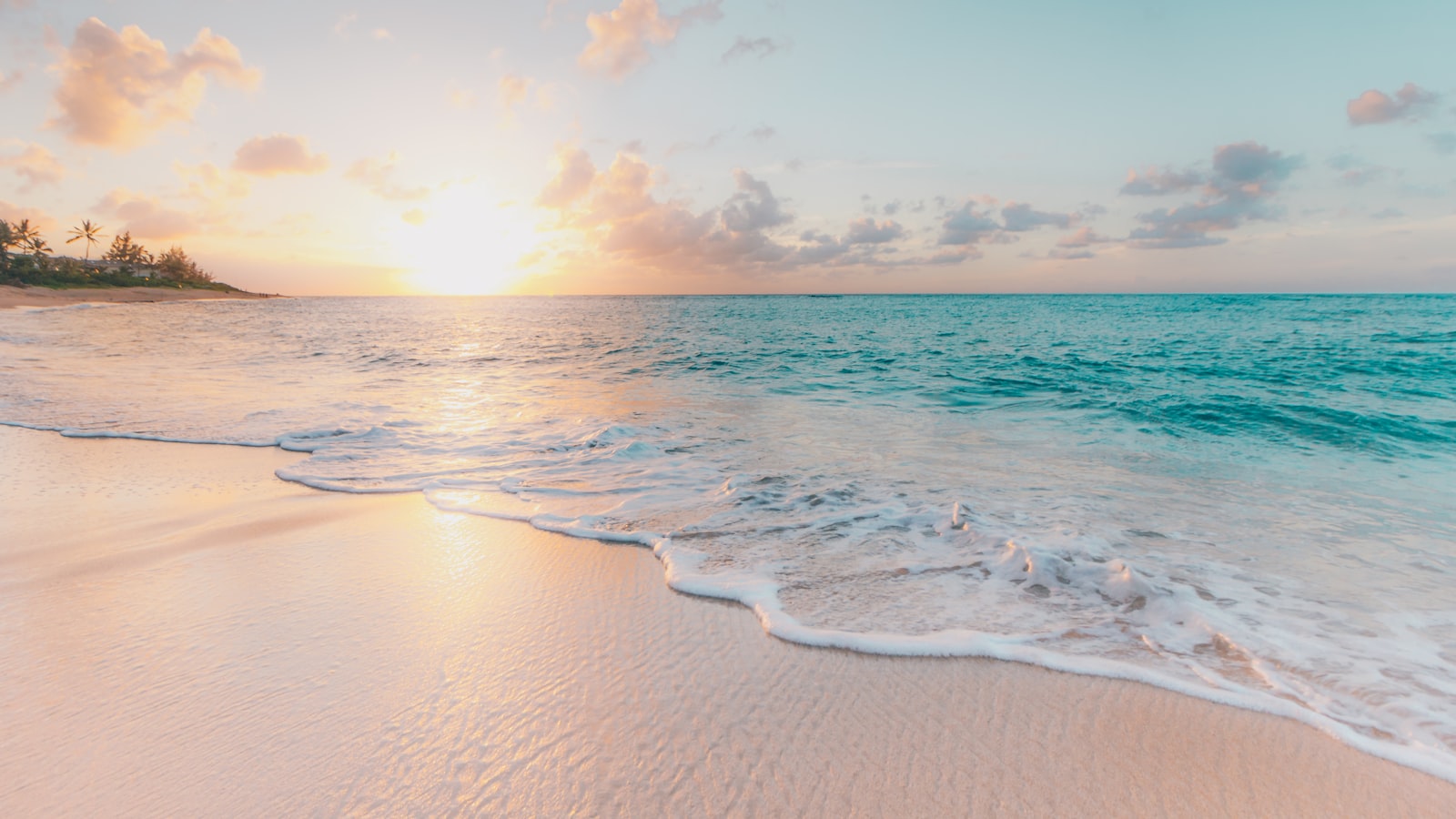 A solo traveller standing on a quiet beach at sunrise looking out at the horizon